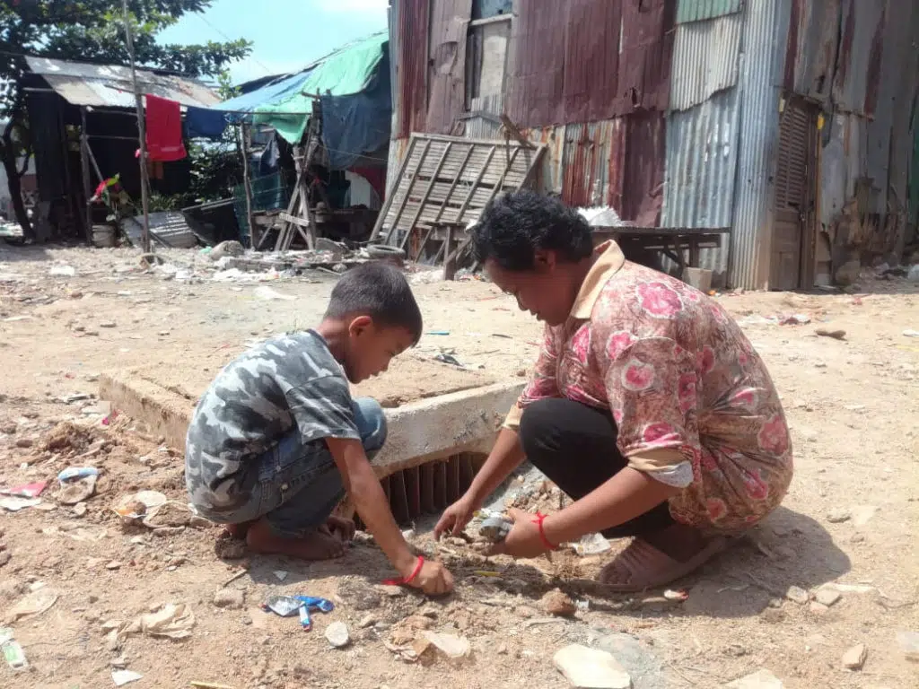 Une mère et son fils participent au nettoyage du site de drainage