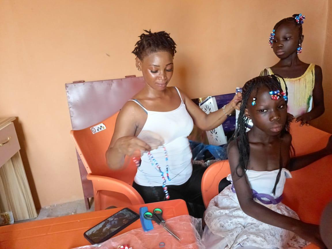 Mariam en train de faire des tresses à une fillette