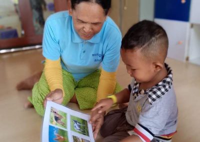 Petit garçon en train de regarder des images avec l'auxiliaire Petite Enfance